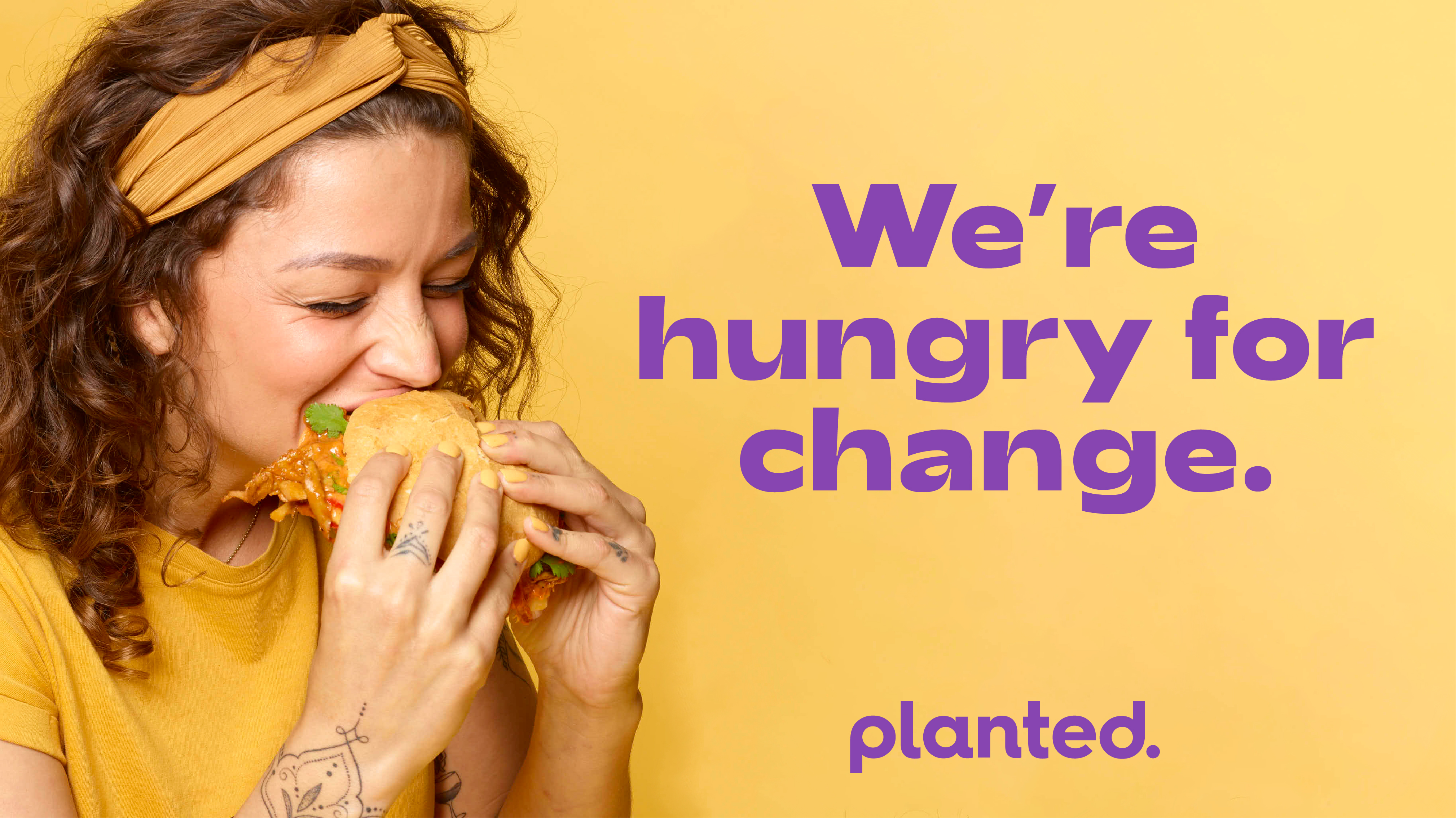 'We're hungry for change.' — a woman eating a sandwich on a yellow background