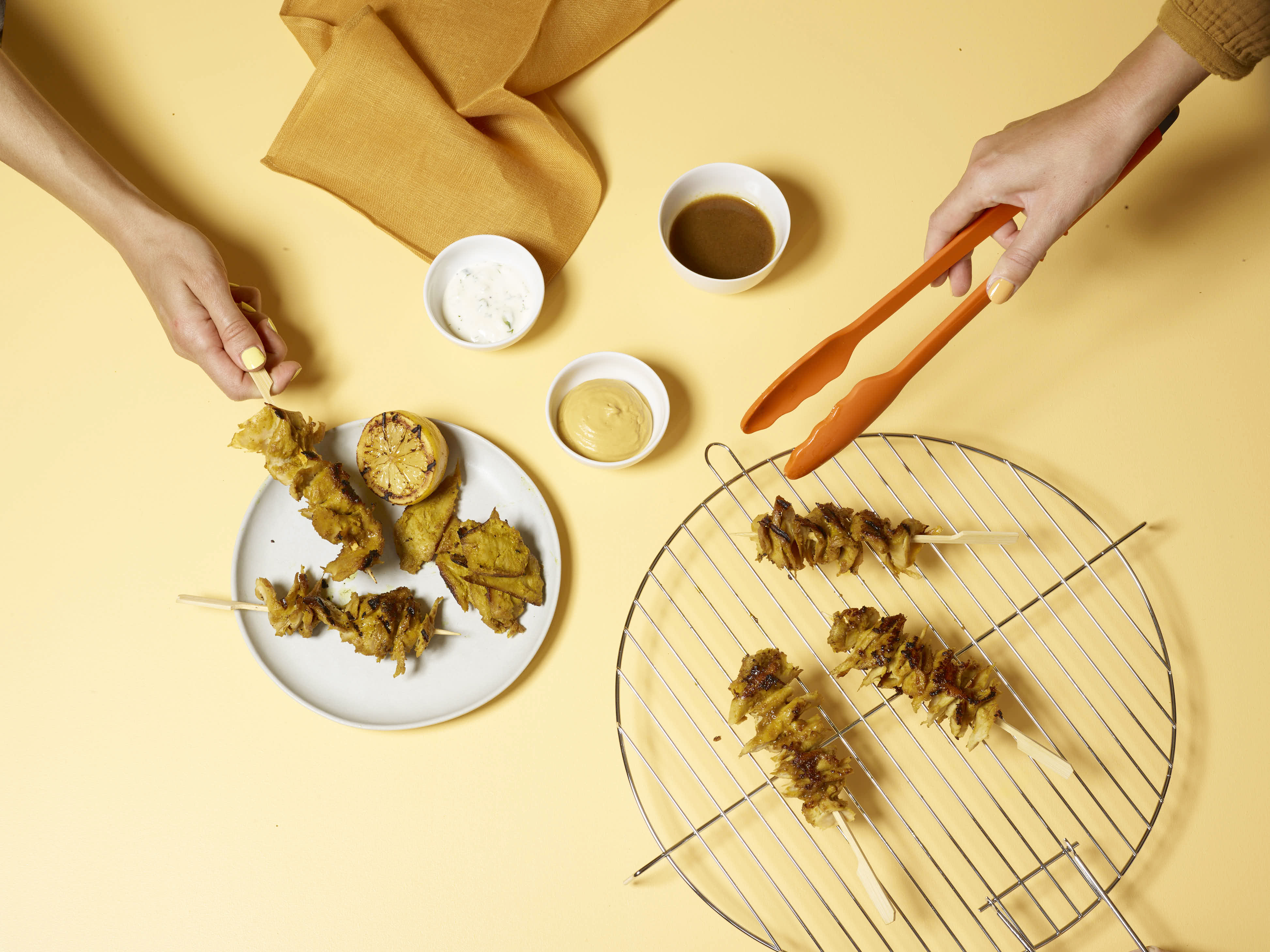Grilled planted.chicken skewers being plated on a yellow table