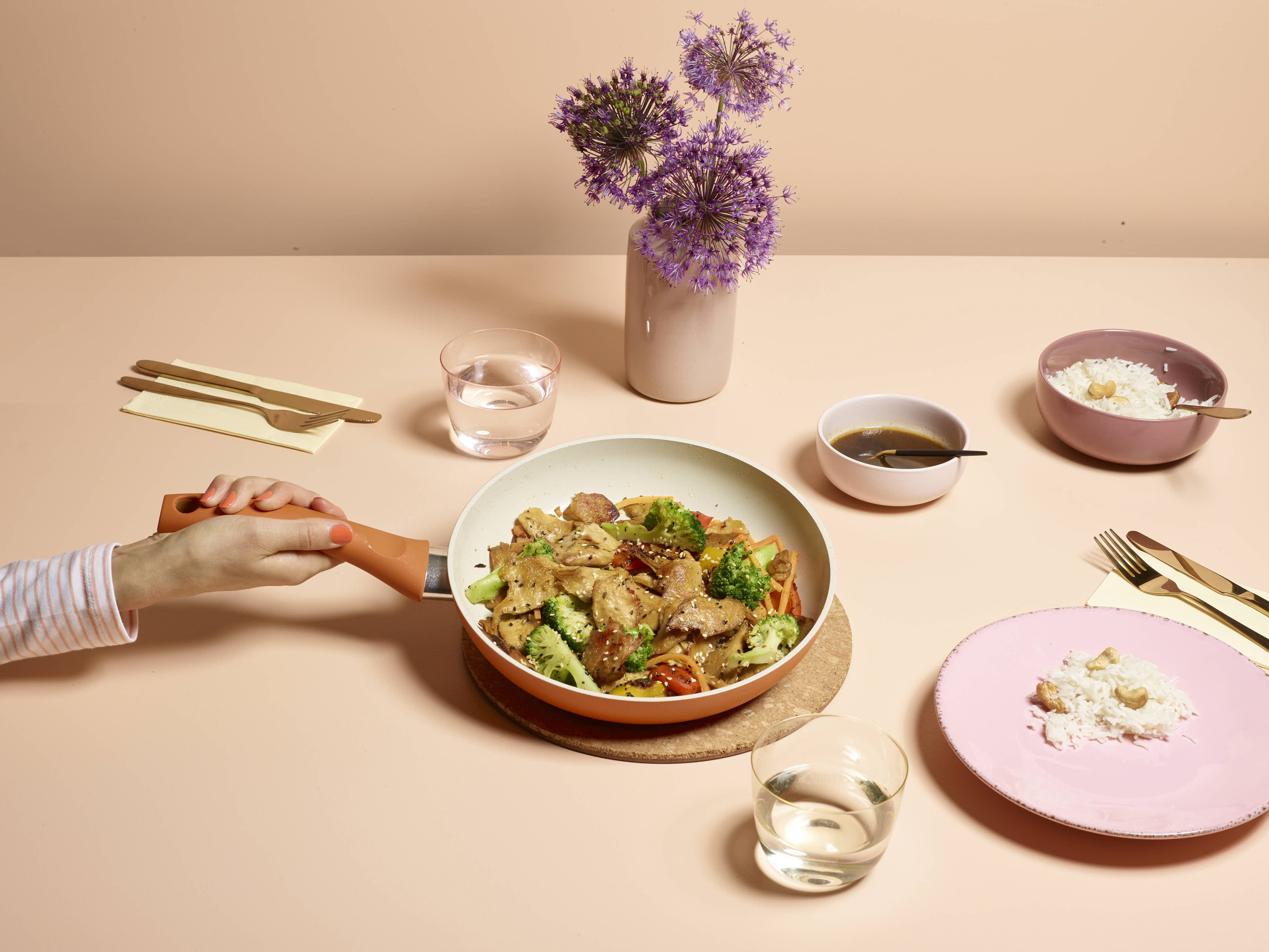A pan of planted.chicken stir-fry with broccoli on a peach table