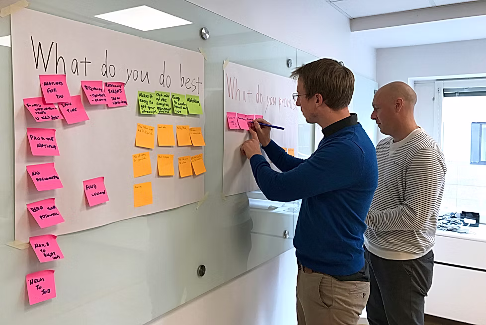 Two people writing on a whiteboard headed 'What do you do best'
