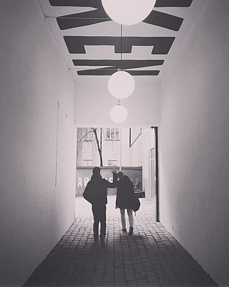 Black and white photo of two people walking down a corridor towards an office entrance