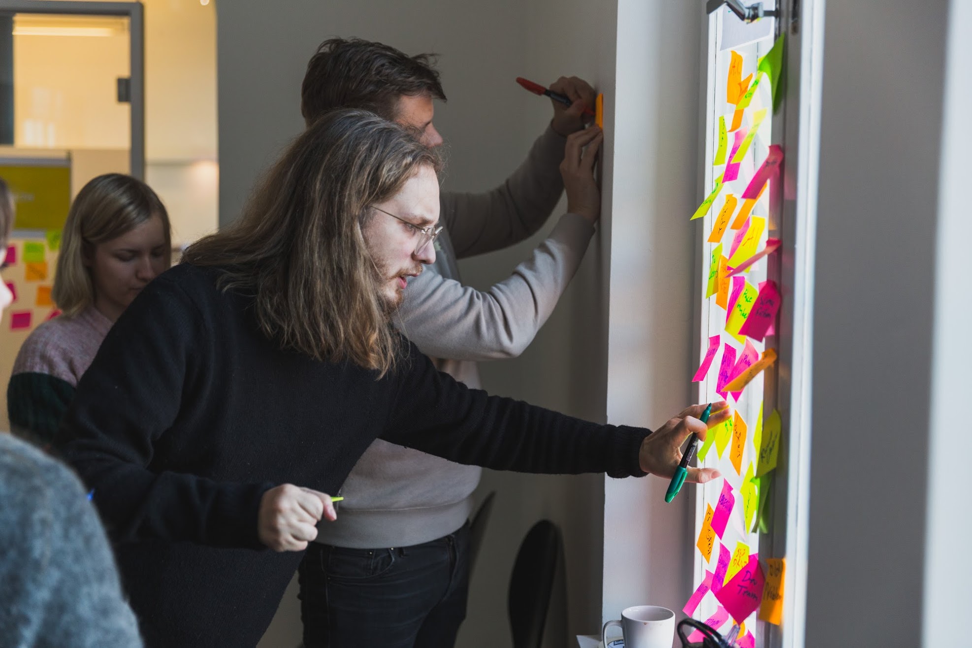 Participants placing sticky notes on a glass wall